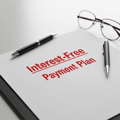 Close-up of a document with 'Interest-Free Payment Plan' highlighted, with a pen and glasses nearby